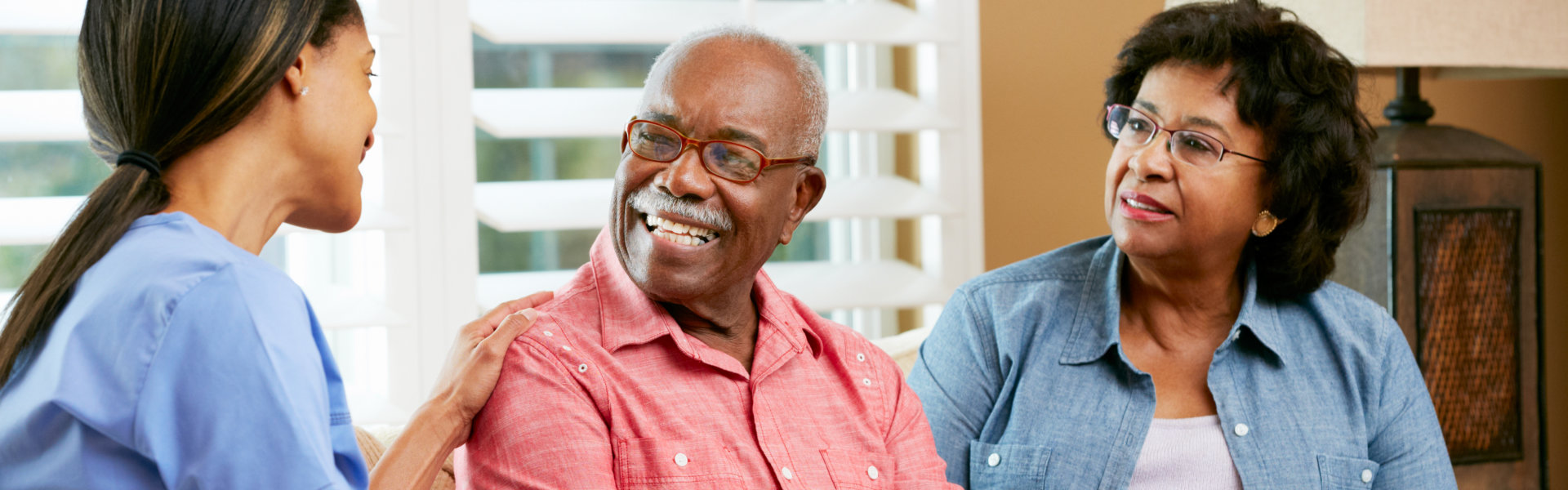 Nurse Making Notes During Home Visit With Elderly Couple