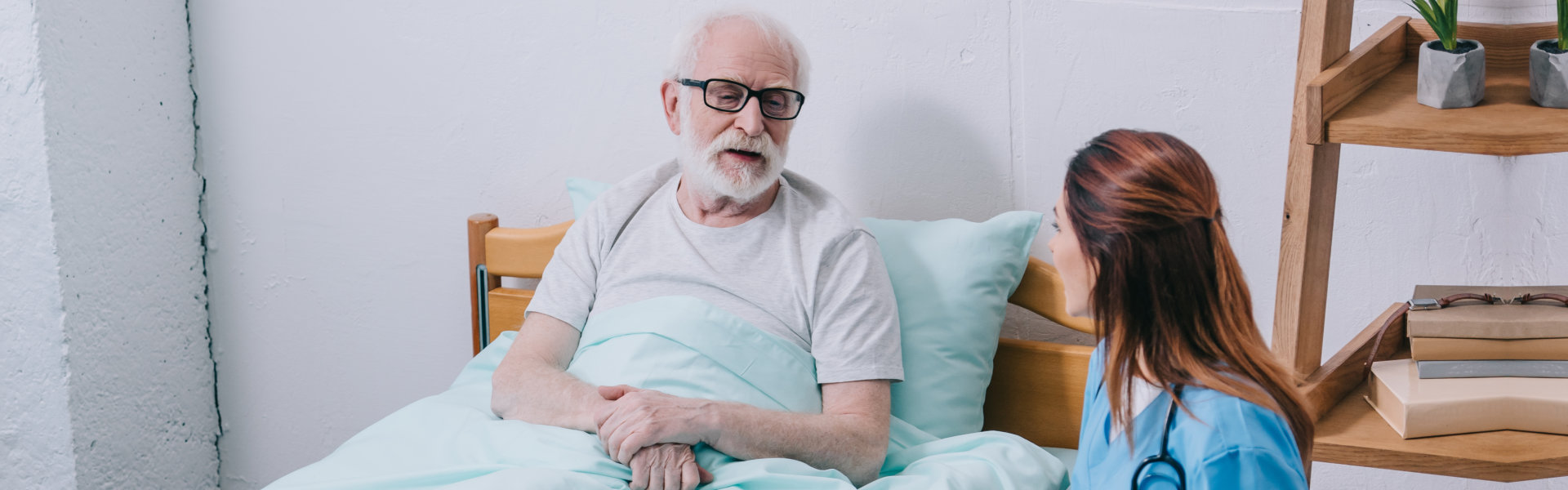 a nurse checking out an elder in his bed