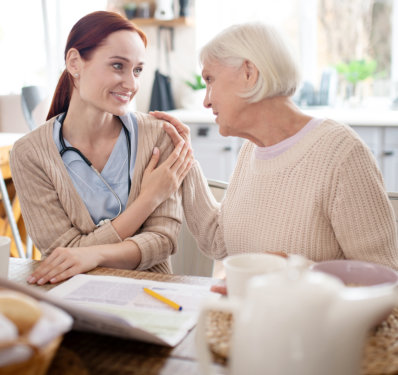 Grey-haired woman feeling thankful to her caregiver