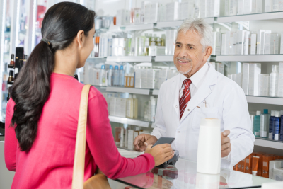 pharmacist looking at female making payment in pharmacy