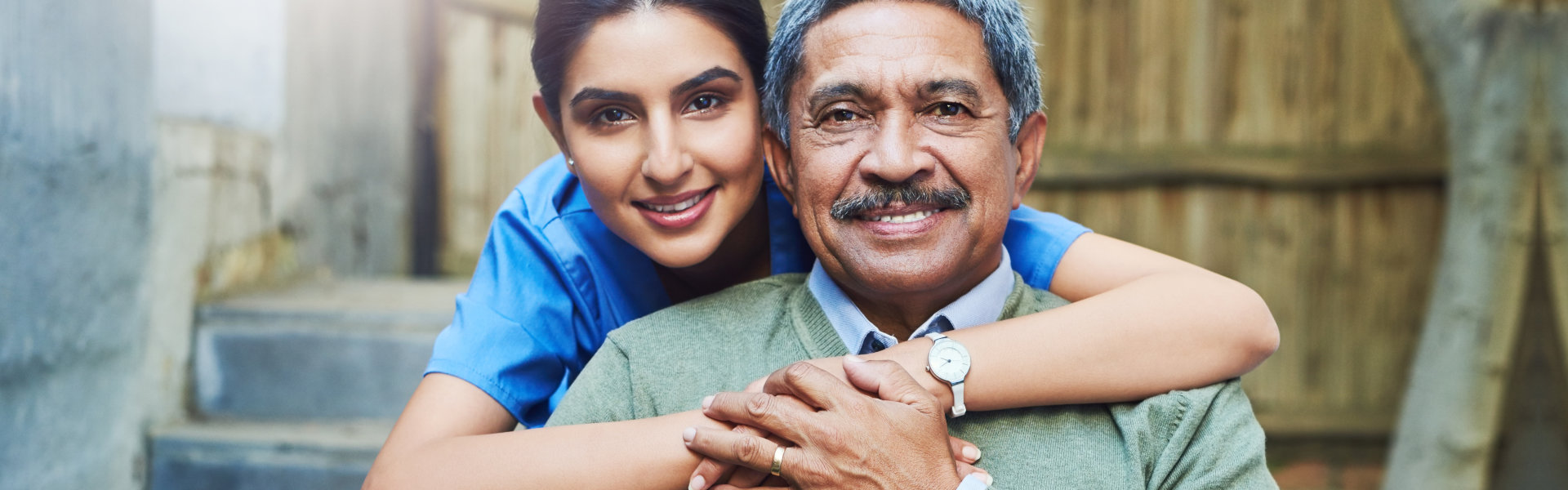 aide hugging the senior man and smiling
